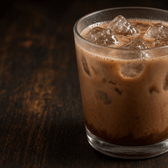 Foto es cokelat aren dengan es batu dalam gelas kaca di meja kayu gelap